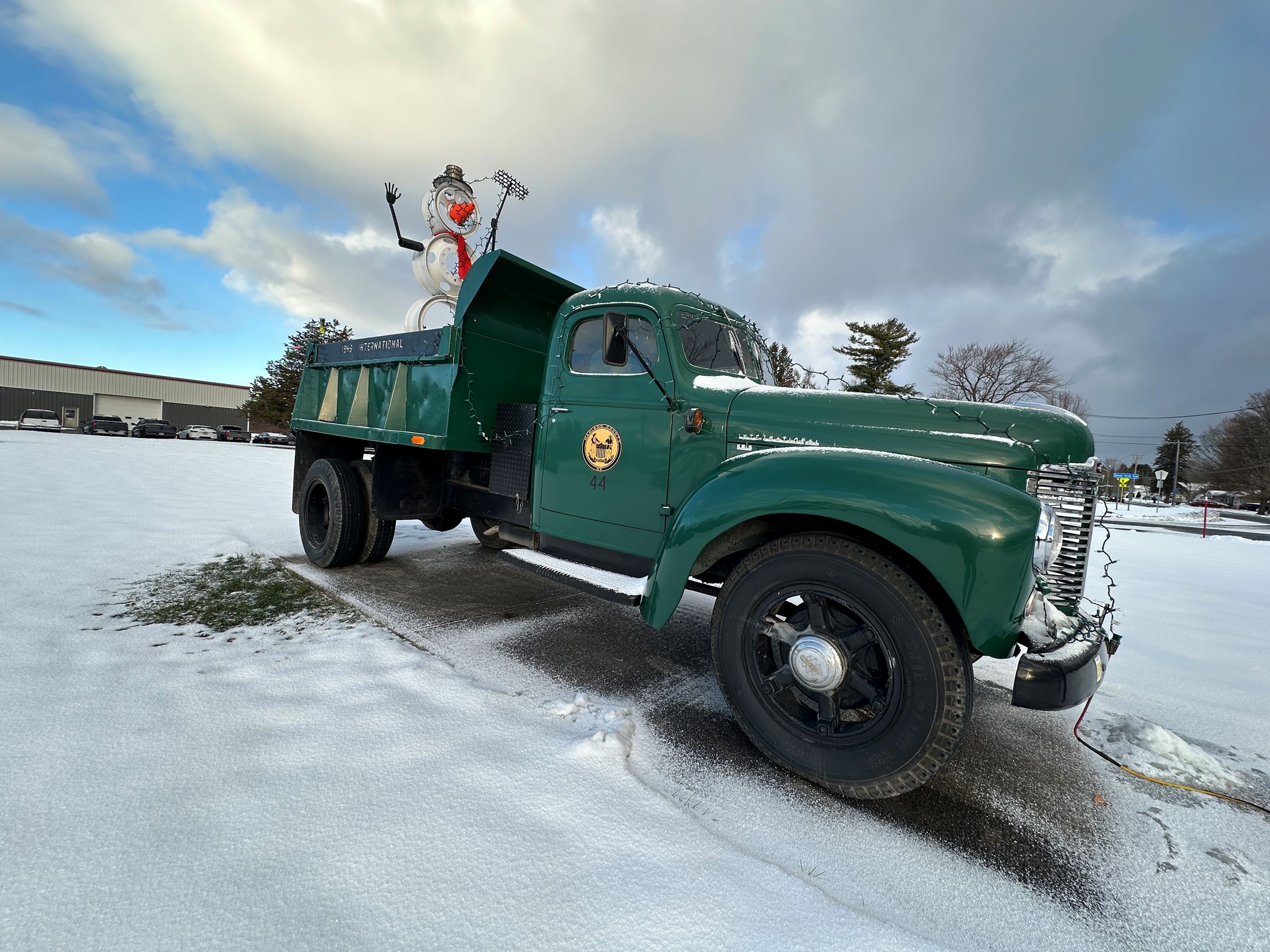 Old green highway truck with snowman on the back in the snow